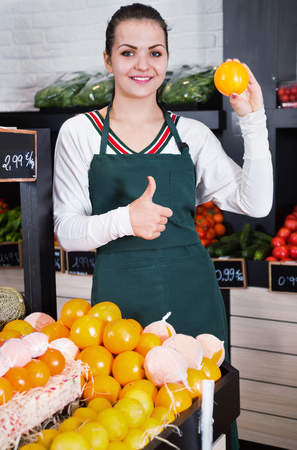Young satisfied pleasant smiling shopping assistant demonstrating assortment of grocery shopの写真素材