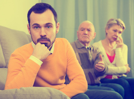 Elderly grandfather talking seriously and instructs his grandson at homeの写真素材