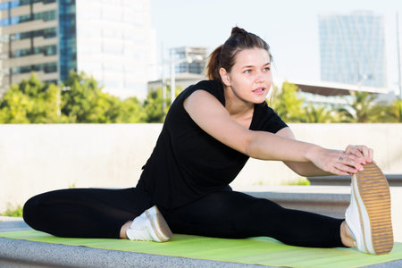 Young smiling woman training healthy lifestyle, doing stretching outdoors