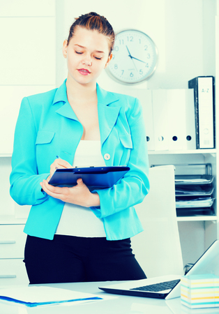 Office worker woman is signing contract at office.の写真素材