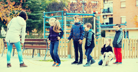 Girl jumping with skipping rope among friends in parkの写真素材