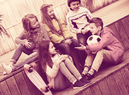 Group of cheerful junior school children chatting and laughing outdoorsの写真素材