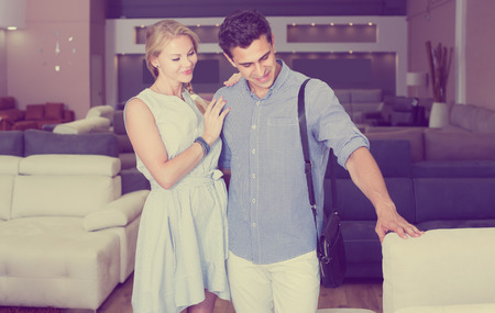 Happy couple are choosing new sofa in furniture store.の写真素材