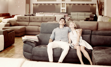 Portrait of a couple who are choosing new sofa-transformer in the store.の写真素材