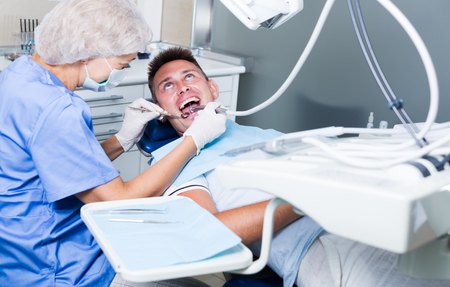 Young man visiting dentist, taking care of his health and dental hygieneの写真素材
