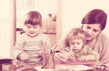 Woman and two children together with pencils in home interiorの写真素材