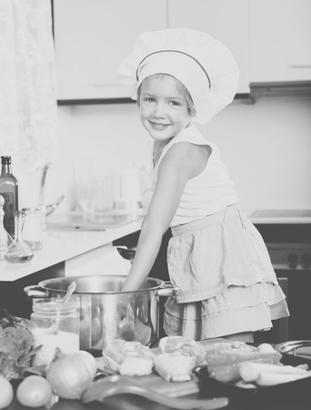 Smiling child cooking soup at kitchenの写真素材