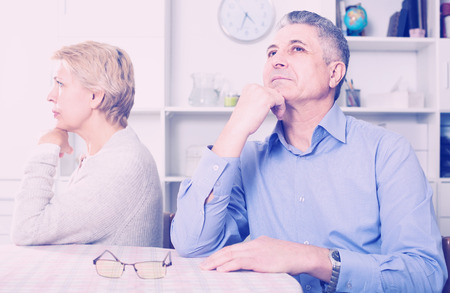 mature russian husband and wife arguing with each other and try to resolve family conflict at tableの写真素材