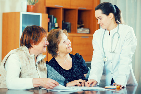 Professional female doctor consulting mature women in clinic interiorの写真素材