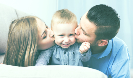 Portrait of cheerful happy young family sitting on sofa at homeの写真素材