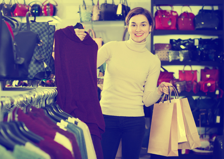 Glad woman enjoying her purchases in womens cloths shopの写真素材