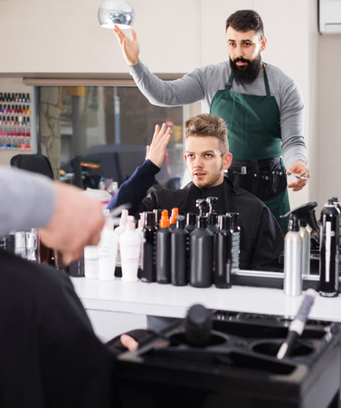 adult european client feeling discontent about his new haircut at hair salonの写真素材