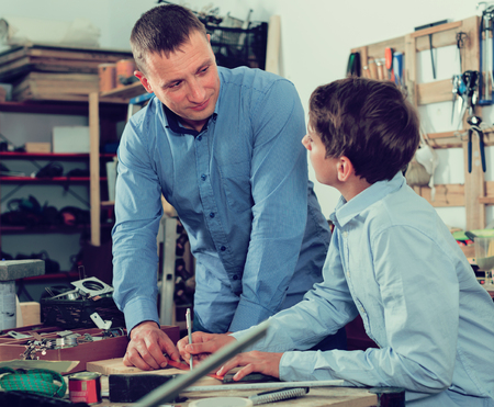 happy spanish adult father teaching son ?arpentry in the garageの写真素材