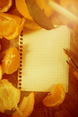 Leaf notebook with writing utensils surrounded by fruitの写真素材