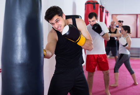 Athletic man is beating a boxing bag in the boxing hall.の写真素材