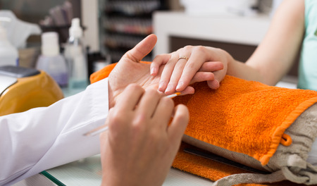 Closeup of woman hands receiving manicure and nail care procedureの写真素材