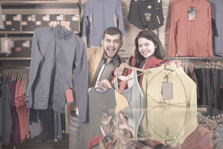 Cheerful couple boasting various sportswear items in sports clothes storeの写真素材