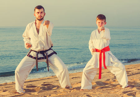 Smiling man and little boy exercising karate in morning outdoorの写真素材