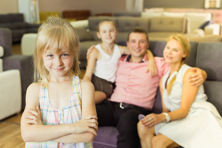 Happy girl children is standing near new sofa in furniture storeの写真素材