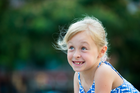 Closeup happy little girl posing on green city landscapeの写真素材