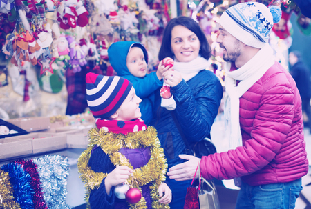 Smiling family with children purchasing decoration and souvenirs at Christmas marketの写真素材