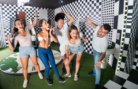 Group of young smiling  positive people having fun in escape room stylized under chessboardの写真素材