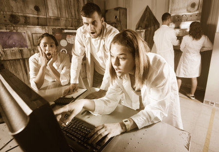 Company of young people solving different conundrum in quest room in view as abandoned lab