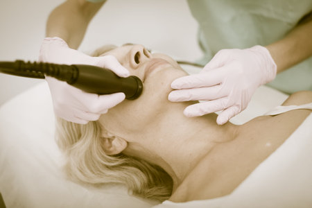 Close up of mature female getting facial cryolipolyse treatment in cosmetic cabinetの写真素材