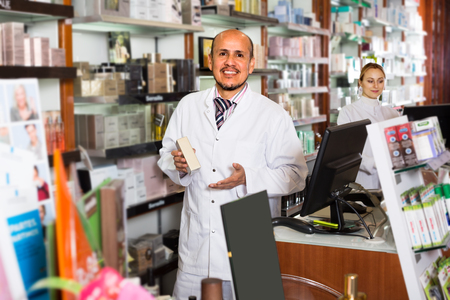 ?Two cheerful  pharmacists standing with a cash desk in the pharmacyの写真素材