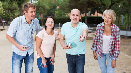 Cheerful males and females playing petanque in th park on holidaysの写真素材