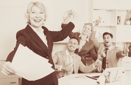 Happy team with businesswoman on foreground emotionally gesturing and celebrating victory at officeの写真素材