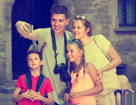 Wife with husband and children are traveling together, taking selfie near city sights.の写真素材