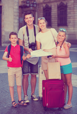 Young parents with two kids traveling together searching location on paper mapの写真素材