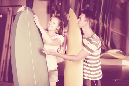 Male is showing to female the surfboard in time summer holidaysの写真素材