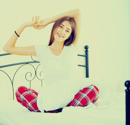 Happy female teenager with long hair relaxing in bedの写真素材