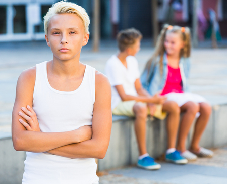 Portrait of offended boy not talking with friends after quarrel outdoorsの写真素材