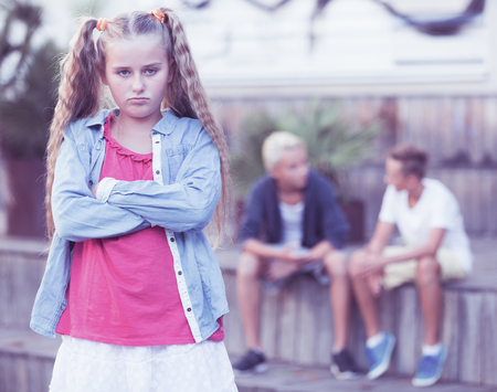 Portrait of sad girl standing apart having problems in relationship with friendsの写真素材
