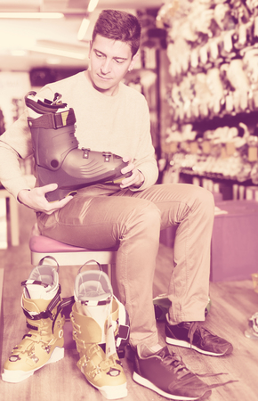 Customer man is trying on new boots for skiing in storeの写真素材