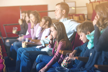 Number of ordinary glad people enjoying film screening and popcorn in cinemaの写真素材