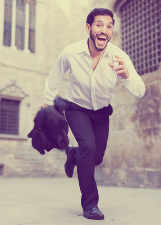 Handsome bearded hurrying man running along old town streetの写真素材