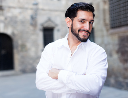 Stylish young man keeping arms crossed and playfully smiling at cameraの写真素材