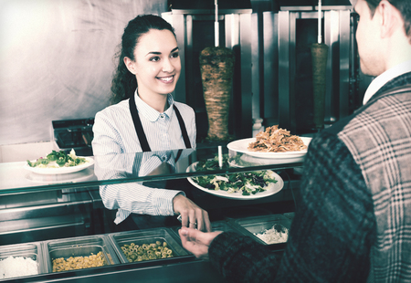 Positive brunette girl and satisfied customer buying kebabの写真素材