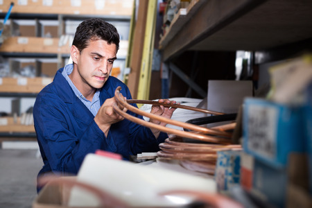 Man assistant is checking rolls of copper trumpet in the building storeの写真素材