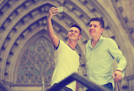 Two guys  with luggage doing selfie at vacationの写真素材