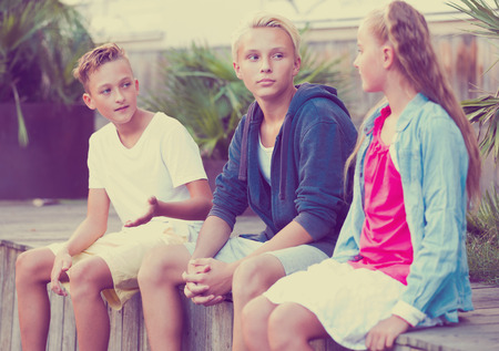 Group of positive children relaxing and chatting in town square gardenの写真素材