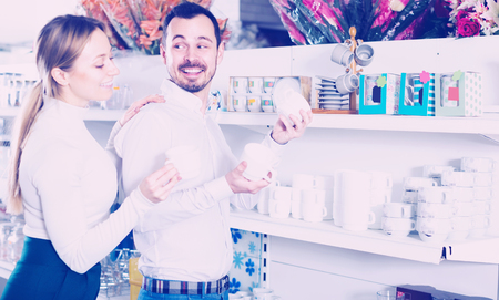 Smiling couple examining ceramic tableware in dinnerware storeの写真素材