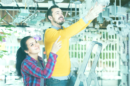 happy american man and girl in lighter shop choosing modern round glass ceiling lamp for houseの写真素材
