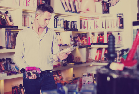 Portrait of serious adult man choosing erotic toys in sex shopの写真素材