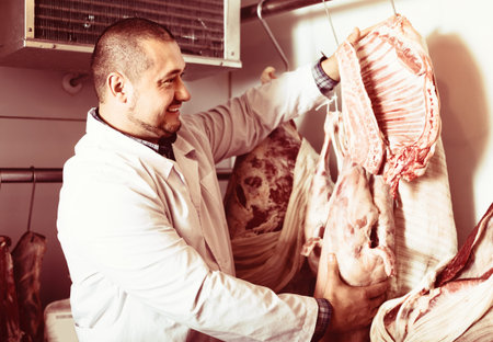 Male shop staff selling kosher meat at counter and smilingの写真素材