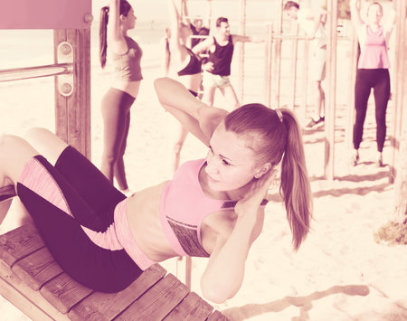 Focusing smiling woman doing workout on beach in sunny morning